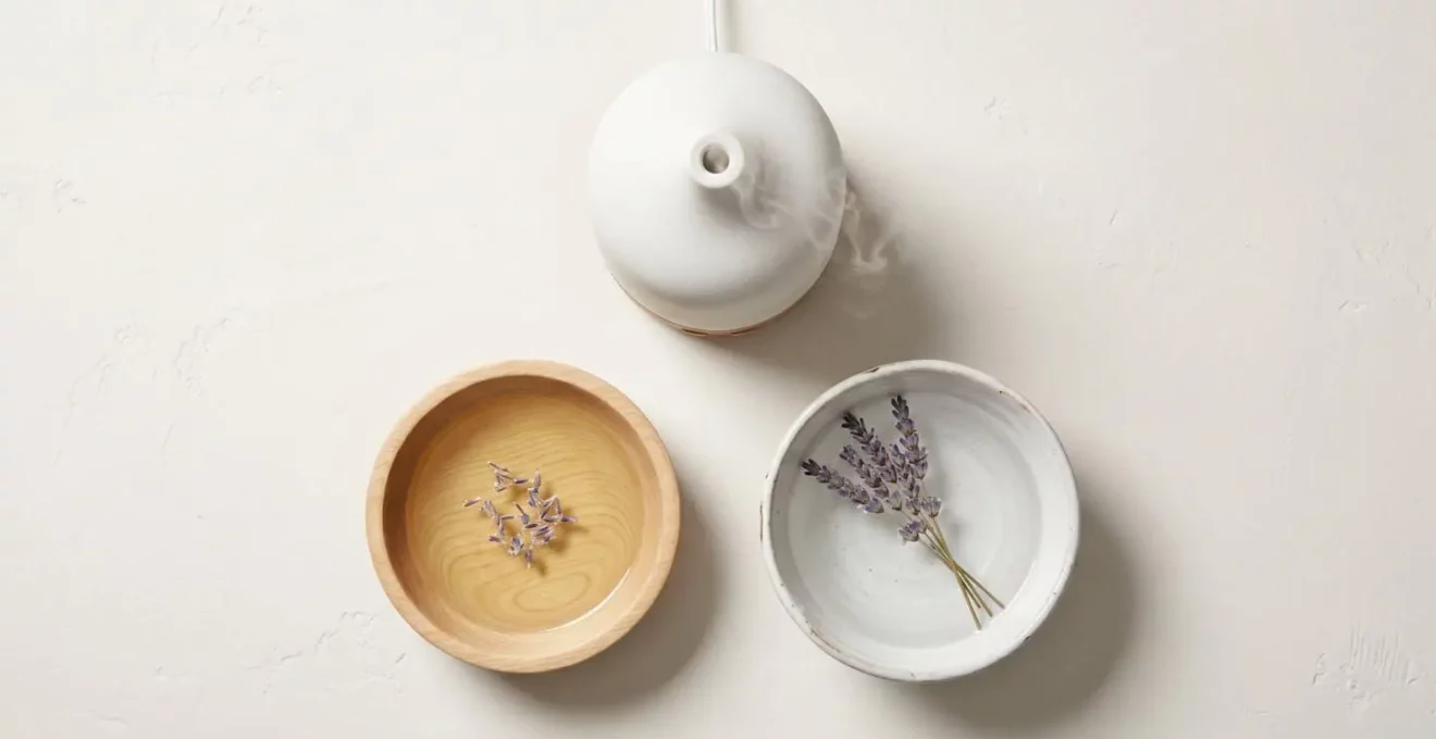 Vue aérienne de trois méthodes d'usage de la lavande : diffuseur avec vapeur, huile végétale avec pétales et bol d'eau avec lavande séchée